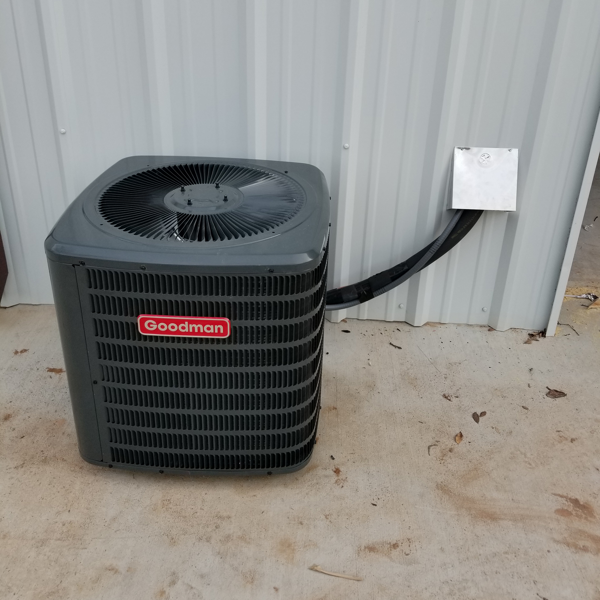 A black air conditioner sitting outside of a building.