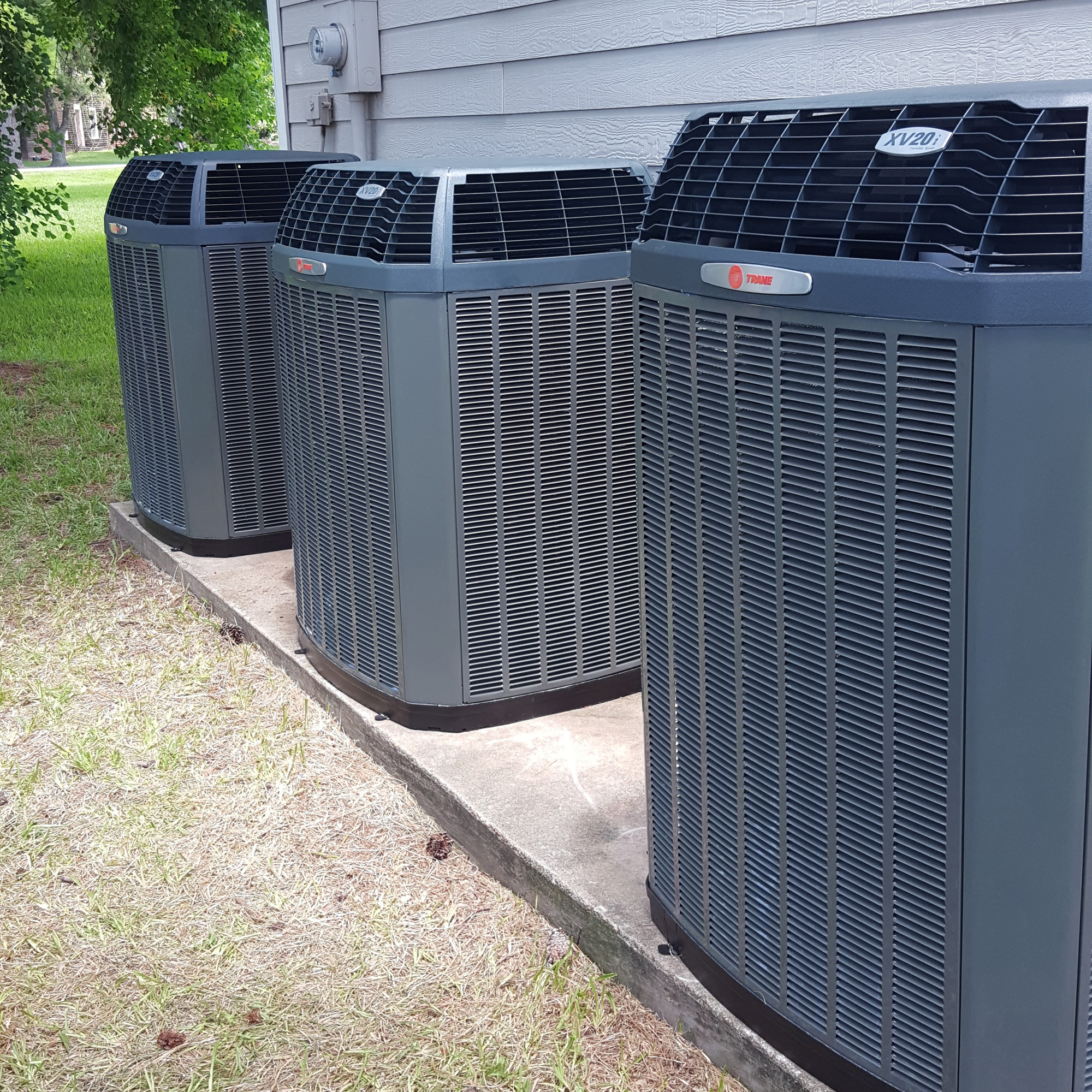 A row of air conditioners sitting outside in the sun.