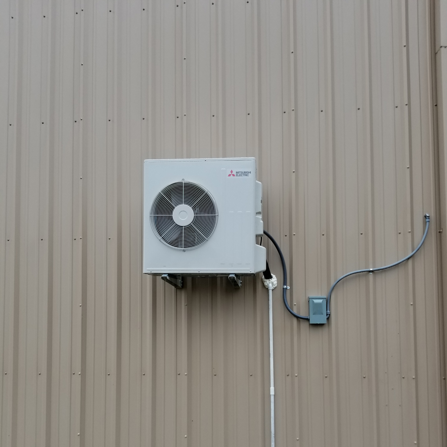 A white air conditioner mounted on the side of a building.