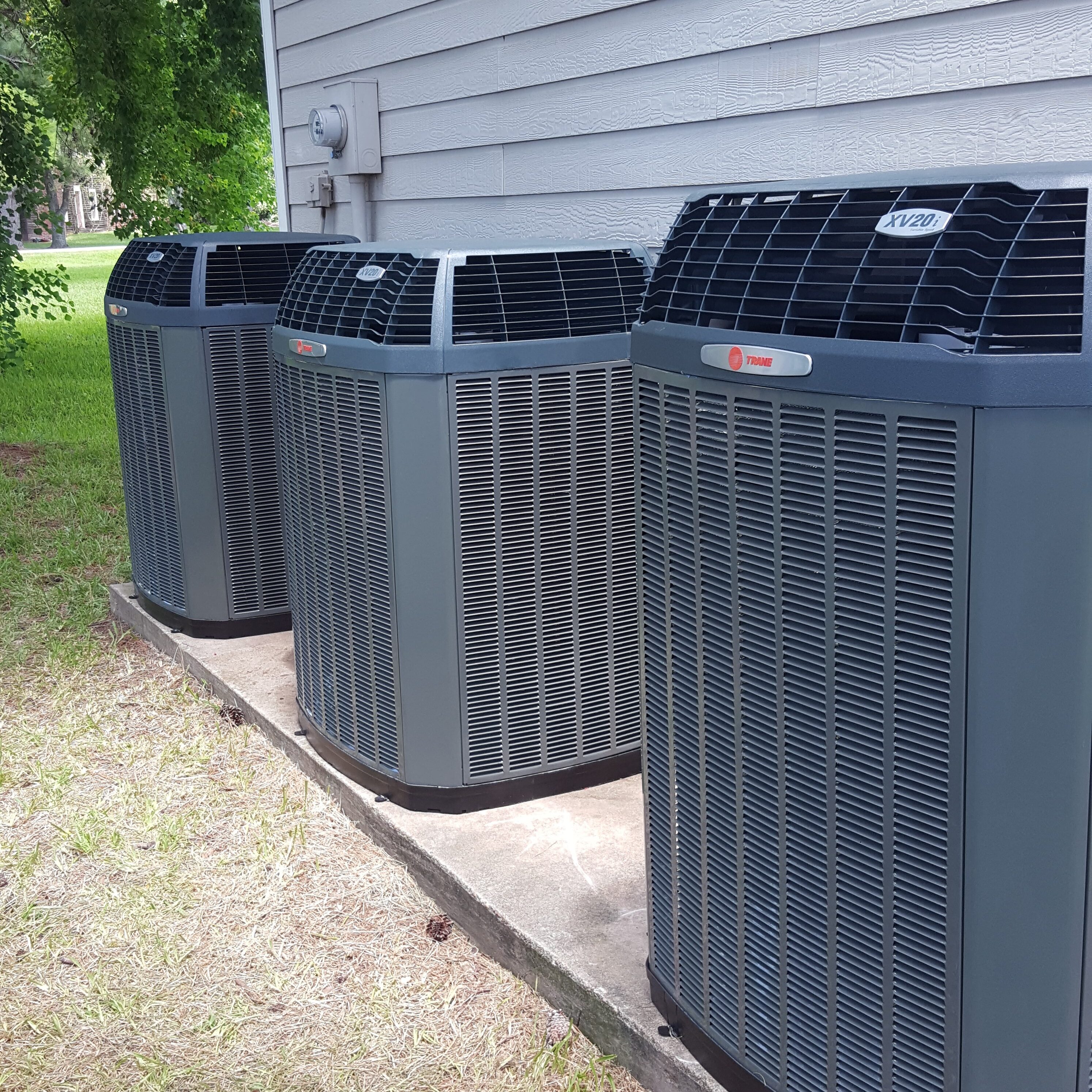 A row of air conditioners sitting outside in the sun.